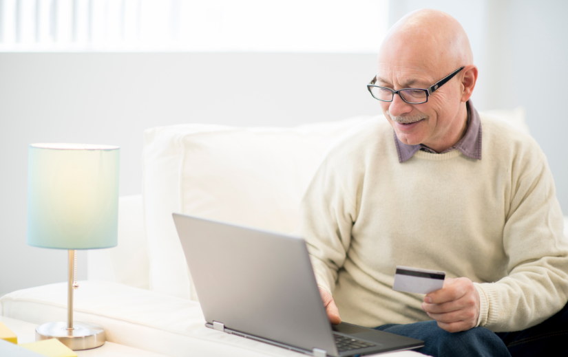 Older man shopping online with a laptop and credit card, demonstrating affiliate marketing strategies in action.